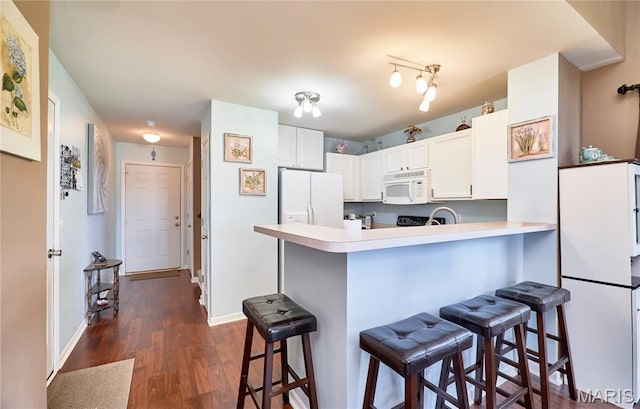228 Centerfield Dr, Ofallon, MO 63366 - kitchen with white appliances, dark wood-style flooring, a kitchen bar, a peninsula, and white cabinets
