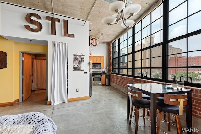 2323 Locust St Unit 308, Saint Louis, MO 63103 - dining room with concrete floors, baseboards, a chandelier, a towering ceiling, and brick wall