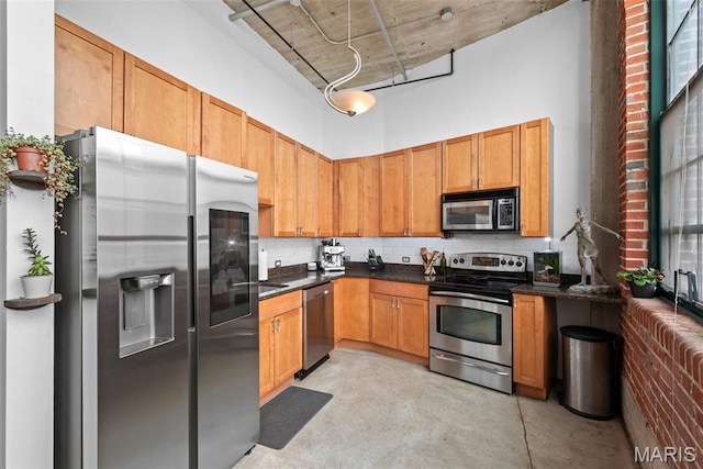 2323 Locust St Unit 308, Saint Louis, MO 63103 - kitchen with stainless steel appliances, finished concrete floors, a towering ceiling, dark countertops, and decorative backsplash