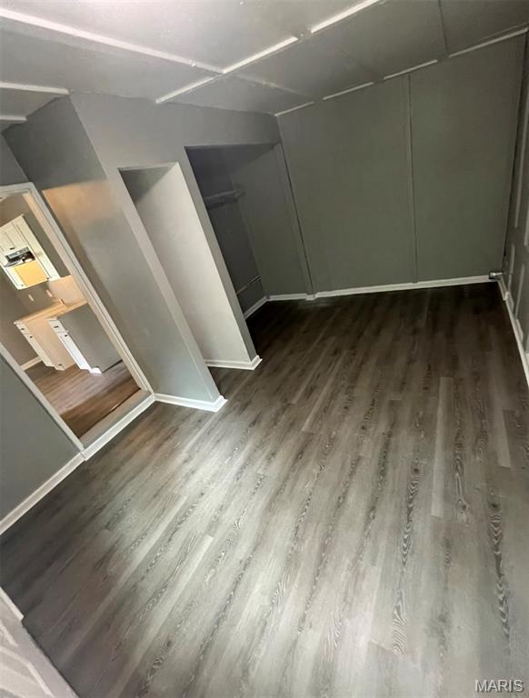 spare room featuring dark wood-style flooring and baseboards