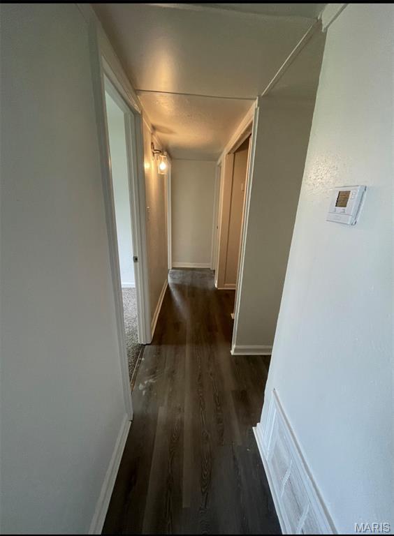 hallway featuring wood finished floors and baseboards