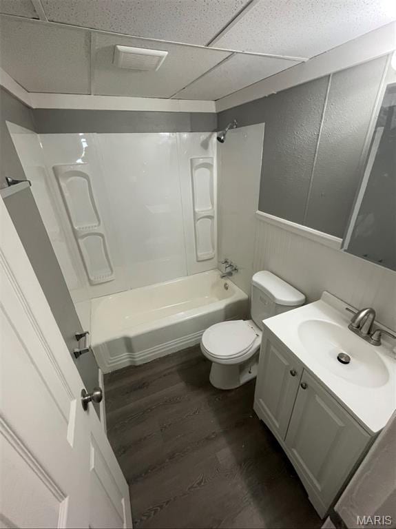 full bathroom with wood finished floors, vanity, tub / shower combination, and wainscoting