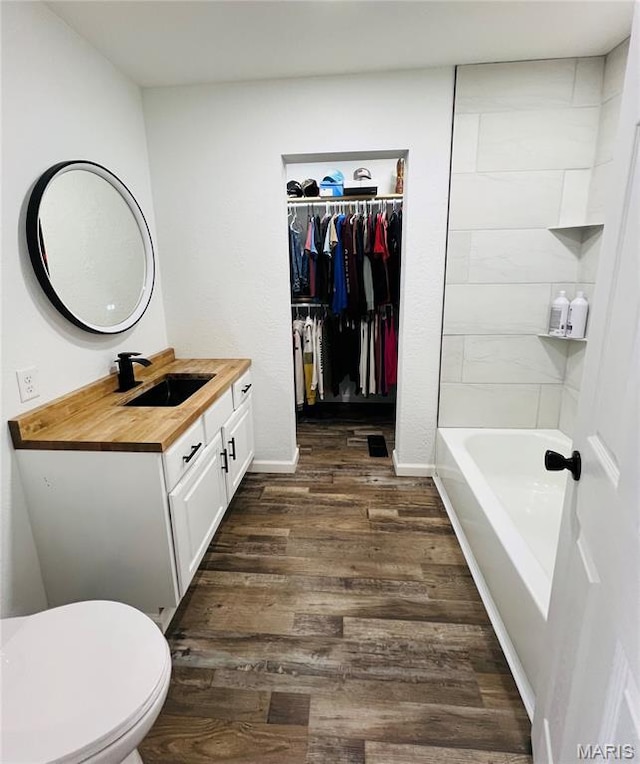 403 E Summit St, Doniphan, MO 63935 - bathroom featuring vanity, wood finished floors, toilet, a spacious closet, and baseboards