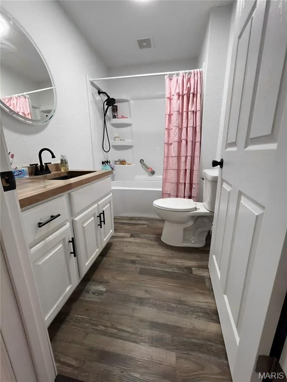 403 E Summit St, Doniphan, MO 63935 - full bath with toilet, vanity, shower / bath combination with curtain, and wood finished floors