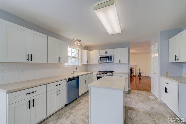 12118 Fahrpark Ln, Saint Louis, MO 63146 - kitchen with appliances with stainless steel finishes, a kitchen island, tasteful backsplash, a sink, and white cabinetry