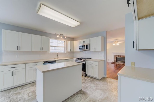 12118 Fahrpark Ln, Saint Louis, MO 63146 - kitchen featuring stainless steel appliances, ceiling fan, white cabinets, decorative backsplash, and light countertops