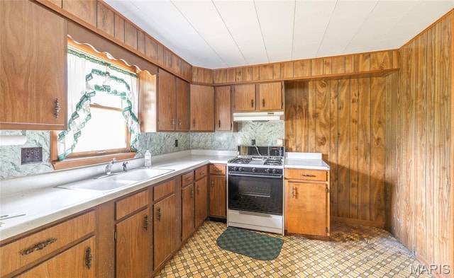 18795 S US Highway 63, Rolla, MO 65401 - kitchen with white gas stove, under cabinet range hood, brown cabinetry, light countertops, and wood walls