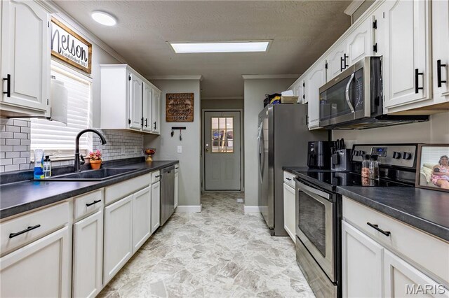 108 Karen St, Sikeston, MO 63801 - kitchen with appliances with stainless steel finishes, a sink, healthy amount of natural light, dark countertops, and crown molding