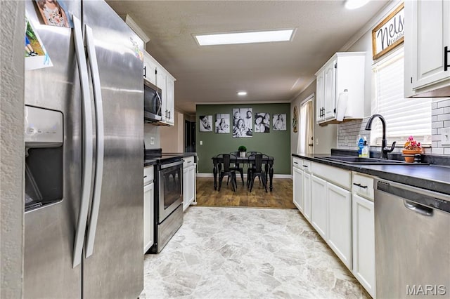 108 Karen St, Sikeston, MO 63801 - kitchen featuring appliances with stainless steel finishes, a sink, dark countertops, and white cabinetry