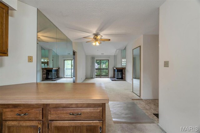 2303 Yosemite Park Ct Unit E, Maryland Heights, MO 63043 - kitchen with a fireplace, light colored carpet, ceiling fan, open floor plan, and a peninsula