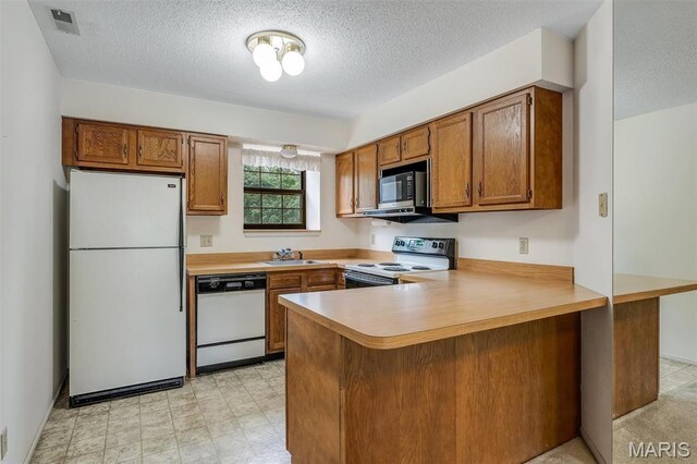 2303 Yosemite Park Ct Unit E, Maryland Heights, MO 63043 - kitchen featuring white appliances, a peninsula, brown cabinetry, light countertops, and a textured ceiling