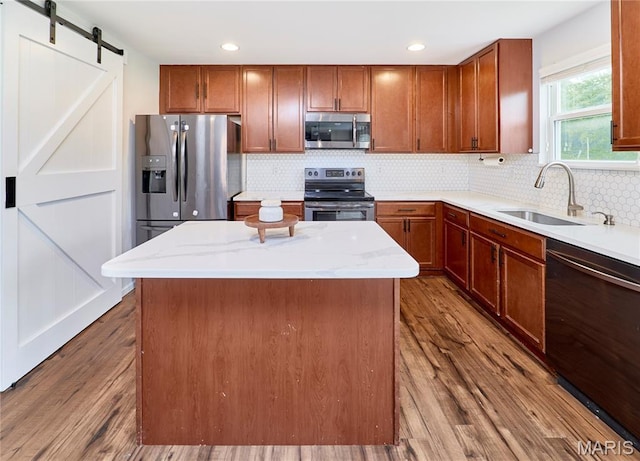 2907 Preston Woods Trl, Lake St Louis, MO 63367 - kitchen featuring appliances with stainless steel finishes, a kitchen island, dark wood-type flooring, decorative backsplash, and light stone counters