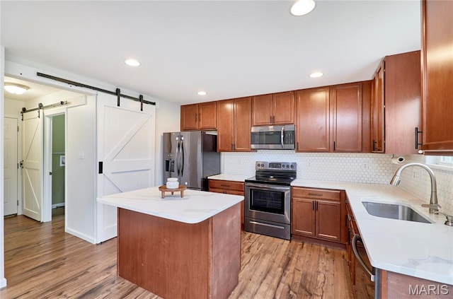 2907 Preston Woods Trl, Lake St Louis, MO 63367 - kitchen featuring stainless steel appliances, a barn door, light wood-type flooring, tasteful backsplash, and recessed lighting