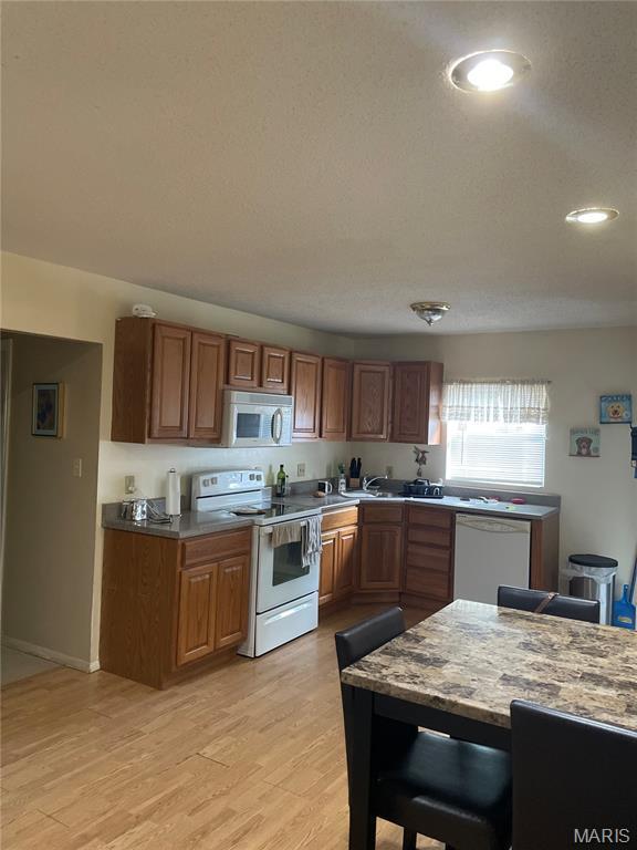 60 La Venta Dr, Florissant, MO 63031 - kitchen with white appliances, light wood-type flooring, brown cabinets, recessed lighting, and baseboards