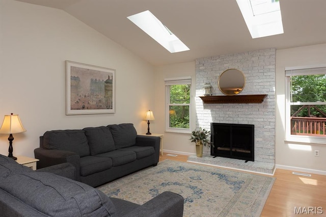 9 Donald Dr, Saint Charles, MO 63304 - living room featuring a skylight, plenty of natural light, a fireplace, vaulted ceiling, and wood finished floors