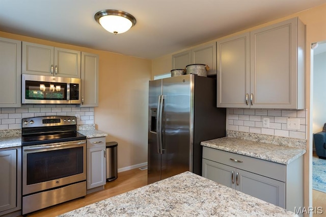 9 Donald Dr, Saint Charles, MO 63304 - kitchen featuring appliances with stainless steel finishes, gray cabinets, light wood finished floors, tasteful backsplash, and light stone countertops