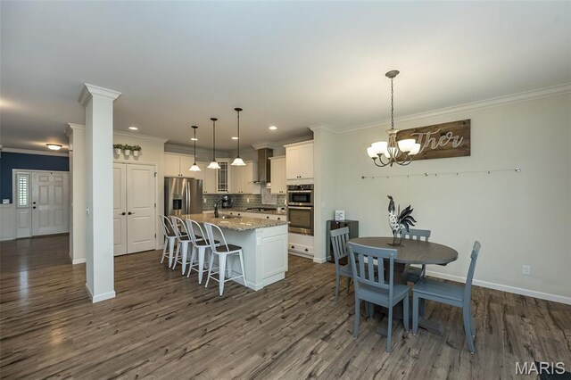 151 Wilmer Valley Dr, Wentzville, MO 63385 - kitchen featuring stainless steel appliances, ornamental molding, wall chimney range hood, tasteful backsplash, and a center island with sink