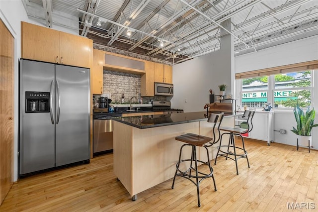 2401 S 12th St Unit 101, Saint Louis, MO 63104 - kitchen with appliances with stainless steel finishes, tasteful backsplash, dark countertops, a center island, and light wood-type flooring