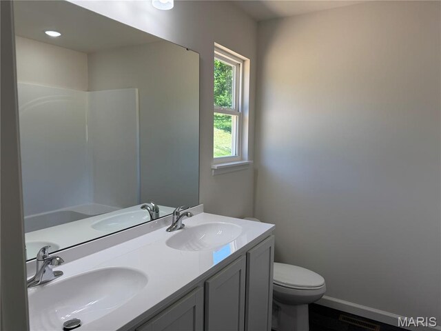2988 Scott Rd, Moscow Mills, MO 63362 - full bathroom featuring toilet, double vanity, baseboards, and wood finished floors