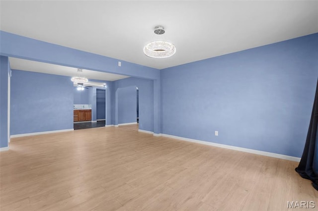 508 Prince Ruppert Dr, Ofallon, MO 63366 - unfurnished living room with a chandelier, baseboards, and light wood-type flooring