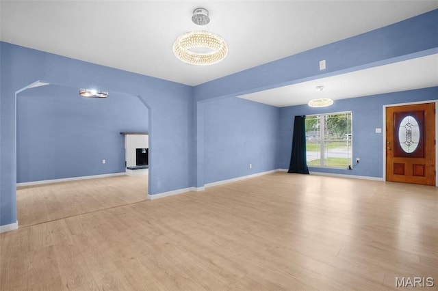 508 Prince Ruppert Dr, Ofallon, MO 63366 - unfurnished living room with arched walkways, wood finished floors, and baseboards