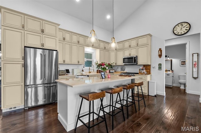 2291 Cambridge, Jackson, MO 63755 - kitchen featuring cream cabinetry, appliances with stainless steel finishes, light countertops, dark wood-style floors, and high vaulted ceiling