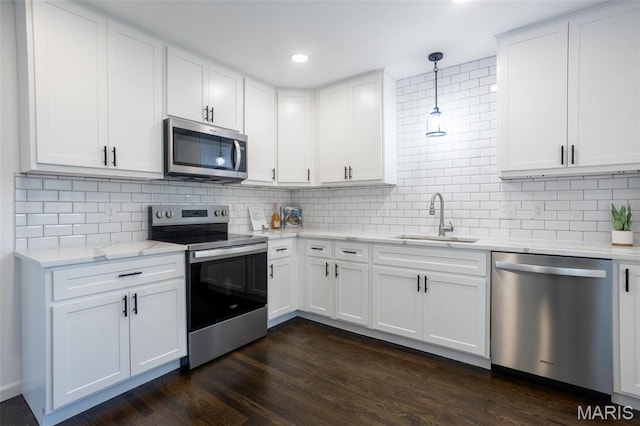 702 Crompton Ct, Saint Louis, MO 63126 - kitchen featuring appliances with stainless steel finishes, tasteful backsplash, white cabinetry, pendant lighting, and dark wood finished floors