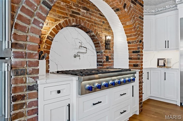 5425 Independence Rd, Weldon Spring, MO 63304 - kitchen with stainless steel gas cooktop, brick wall, wood finished floors, white cabinetry, and light stone counters