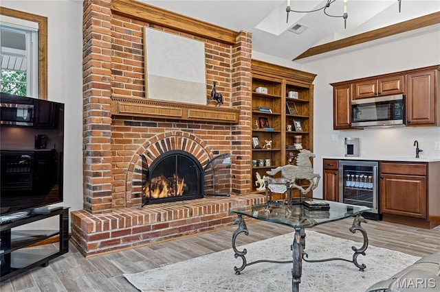 5425 Independence Rd, Weldon Spring, MO 63304 - living area featuring wine cooler, vaulted ceiling, wood finished floors, a fireplace, and bar with sink