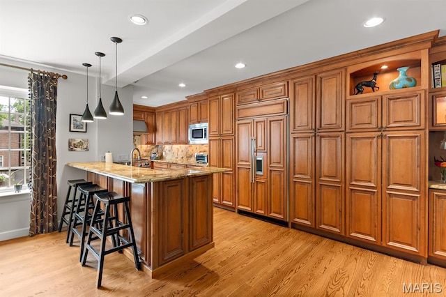 7428 Wellington Way, Clayton, MO 63105 - kitchen with built in appliances, brown cabinets, light wood-style flooring, a kitchen breakfast bar, and recessed lighting