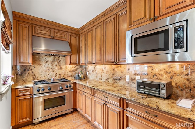7428 Wellington Way, Clayton, MO 63105 - kitchen featuring appliances with stainless steel finishes, exhaust hood, decorative backsplash, brown cabinetry, and light stone countertops