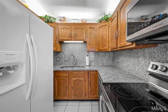 1615 Rosewall Dr Unit C, Saint Charles, MO 63303 - kitchen featuring stainless steel appliances, brown cabinetry, light tile patterned flooring, light stone countertops, and backsplash