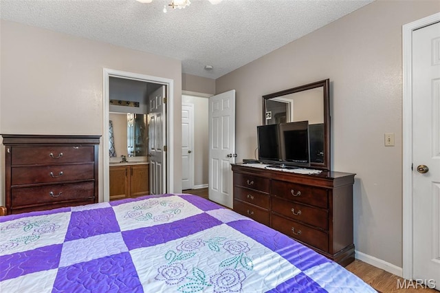 1121 N Desloge Dr Unit J-2, Desloge, MO 63601 - bedroom with baseboards, wood finished floors, a textured ceiling, and connected bathroom