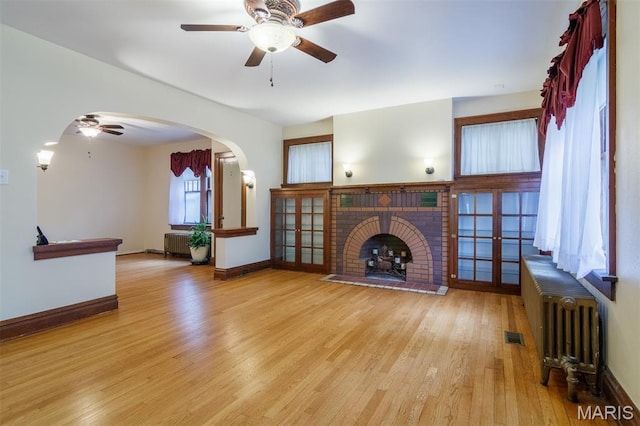 607 9th St, Highland, IL 62249 - unfurnished living room featuring a ceiling fan, wood finished floors, a brick fireplace, radiator, and baseboards
