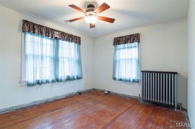 607 9th St, Highland, IL 62249 - unfurnished room featuring radiator heating unit, wood-type flooring, and a ceiling fan