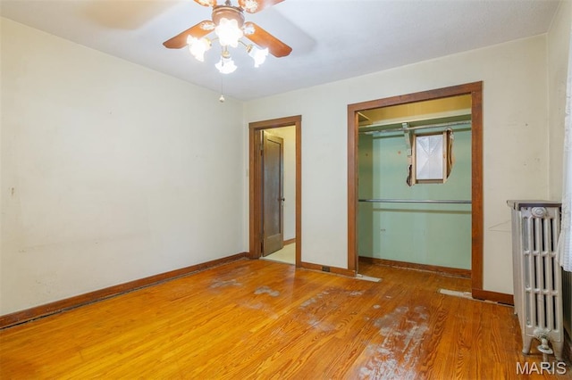 607 9th St, Highland, IL 62249 - unfurnished bedroom featuring radiator, light wood-style flooring, a closet, and a ceiling fan