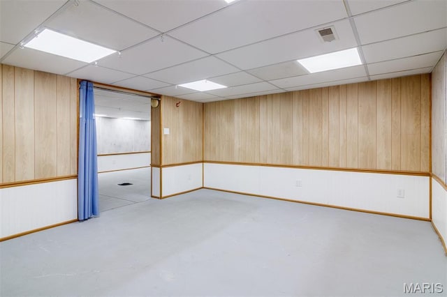 607 9th St, Highland, IL 62249 - empty room featuring a drop ceiling, wood walls, concrete flooring, and baseboards
