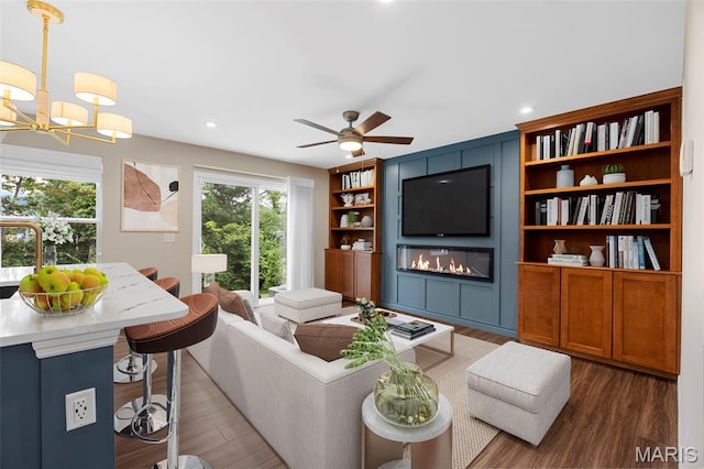 357 Newbridge Way, Ofallon, MO 63368 - living room featuring a fireplace, wood finished floors, a chandelier, ceiling fan, and recessed lighting