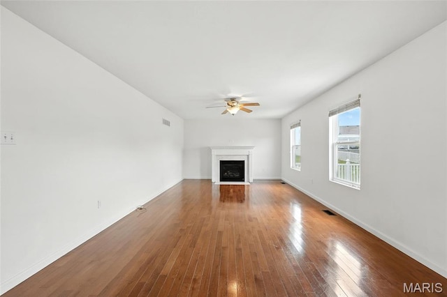429 Red Coat Trl, Wentzville, MO 63385 - unfurnished living room featuring ceiling fan, a fireplace with flush hearth, and wood-type flooring