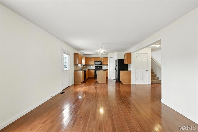 429 Red Coat Trl, Wentzville, MO 63385 - kitchen with black appliances, dark wood-style floors, dark countertops, open floor plan, and decorative backsplash