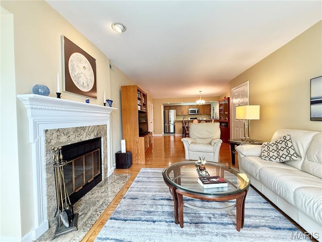4235 W Pine Blvd Unit 21, Saint Louis, MO 63108 - living room featuring a high end fireplace, light wood-style flooring, a chandelier, and baseboards