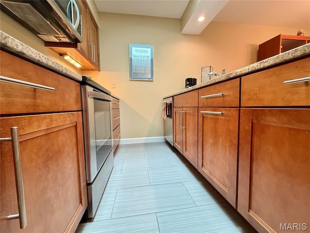 4235 W Pine Blvd Unit 21, Saint Louis, MO 63108 - kitchen with brown cabinets, baseboards, recessed lighting, dark tile patterned flooring, and stainless steel microwave