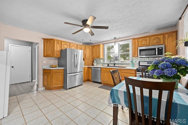 203 N Williams St, Albers, IL 62215 - kitchen featuring appliances with stainless steel finishes, a ceiling fan, light countertops, tasteful backsplash, and brown cabinets