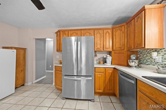 203 N Williams St, Albers, IL 62215 - kitchen featuring stainless steel appliances, light tile patterned floors, light countertops, backsplash, and brown cabinetry