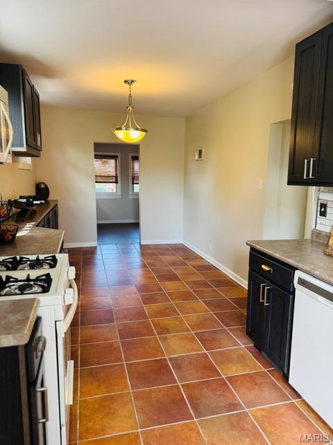 1928 Arsenal St, Saint Louis, MO 63118 - kitchen with white appliances, dark tile patterned flooring, decorative light fixtures, dark cabinets, and light countertops