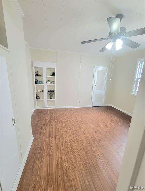 1928 Arsenal St, Saint Louis, MO 63118 - spare room featuring built in features, light wood-type flooring, a ceiling fan, and crown molding