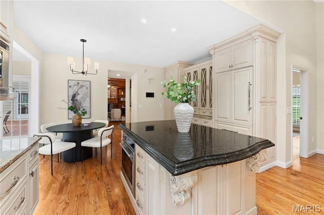 16427 Andraes Dr, Chesterfield, MO 63005 - kitchen featuring a chandelier, light wood finished floors, dark stone counters, a kitchen island, and hanging light fixtures