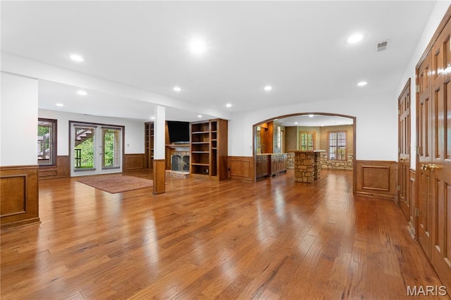 16427 Andraes Dr, Chesterfield, MO 63005 - unfurnished living room featuring wainscoting, a fireplace with raised hearth, recessed lighting, light wood-type flooring, and arched walkways