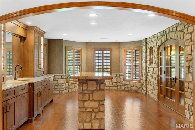 16427 Andraes Dr, Chesterfield, MO 63005 - kitchen with light wood finished floors, glass insert cabinets, a kitchen island, light stone countertops, and brown cabinets