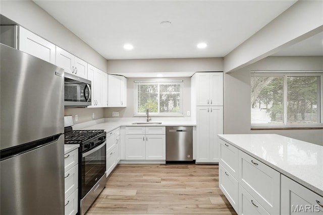 7 Flamingo Dr, Hazelwood, MO 63042 - kitchen featuring stainless steel appliances, light wood-type flooring, white cabinetry, recessed lighting, and light stone countertops
